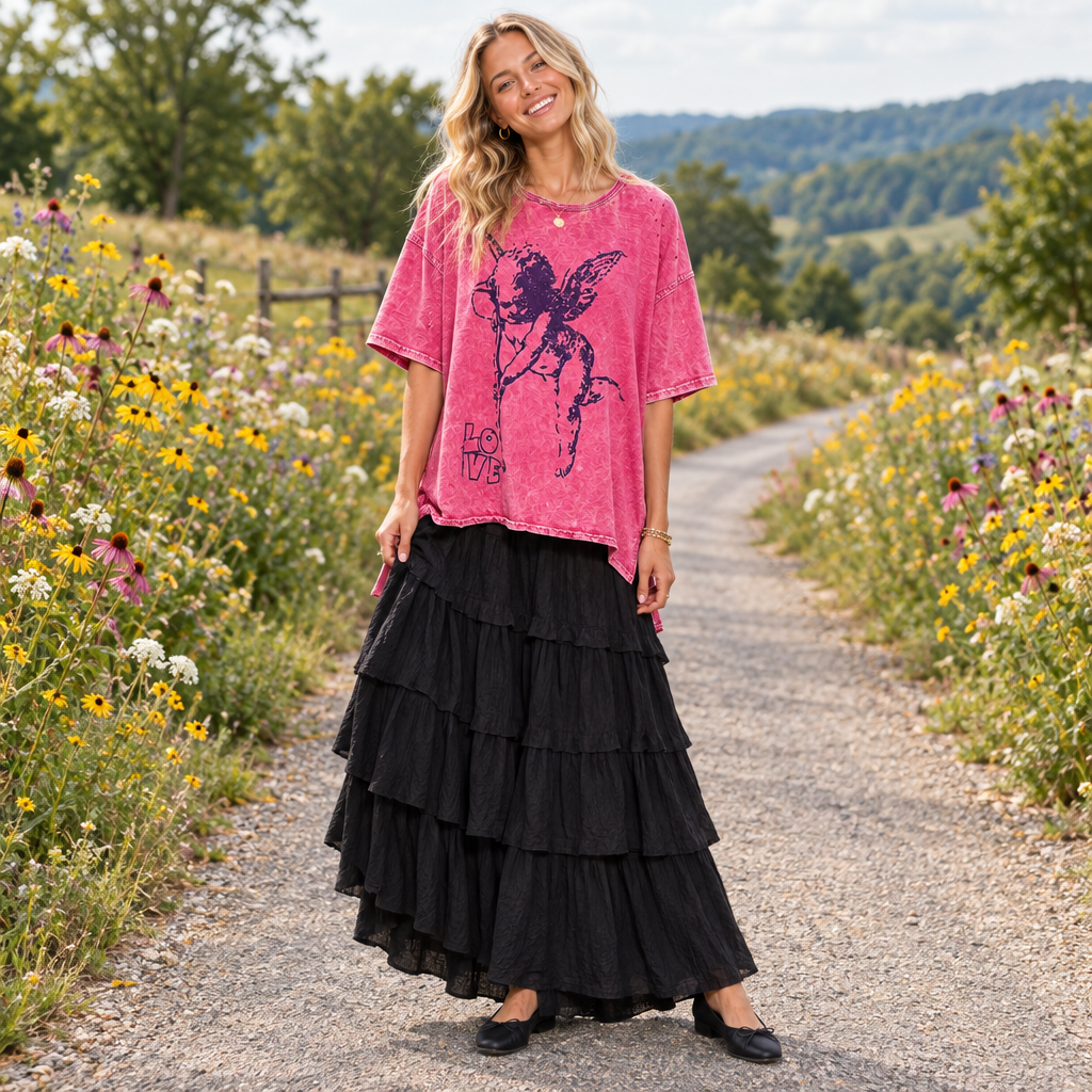 A pink acid-wash short-sleeve t-shirt with a distressed black graphic of a winged cherub and the text 'LOVE' on the front, displayed against a light gray background.
